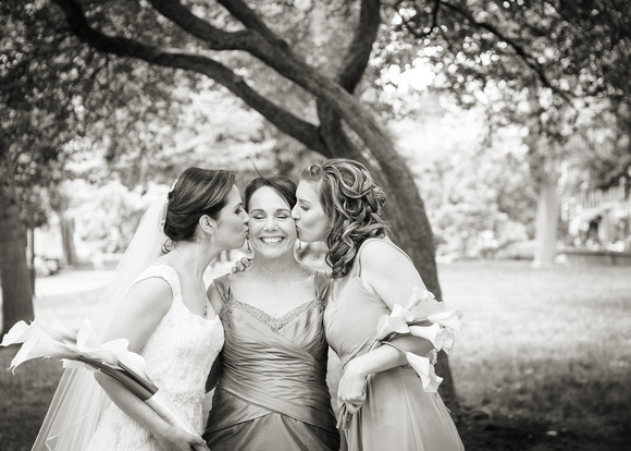 Bride and sister kissing their mom on wedding day.